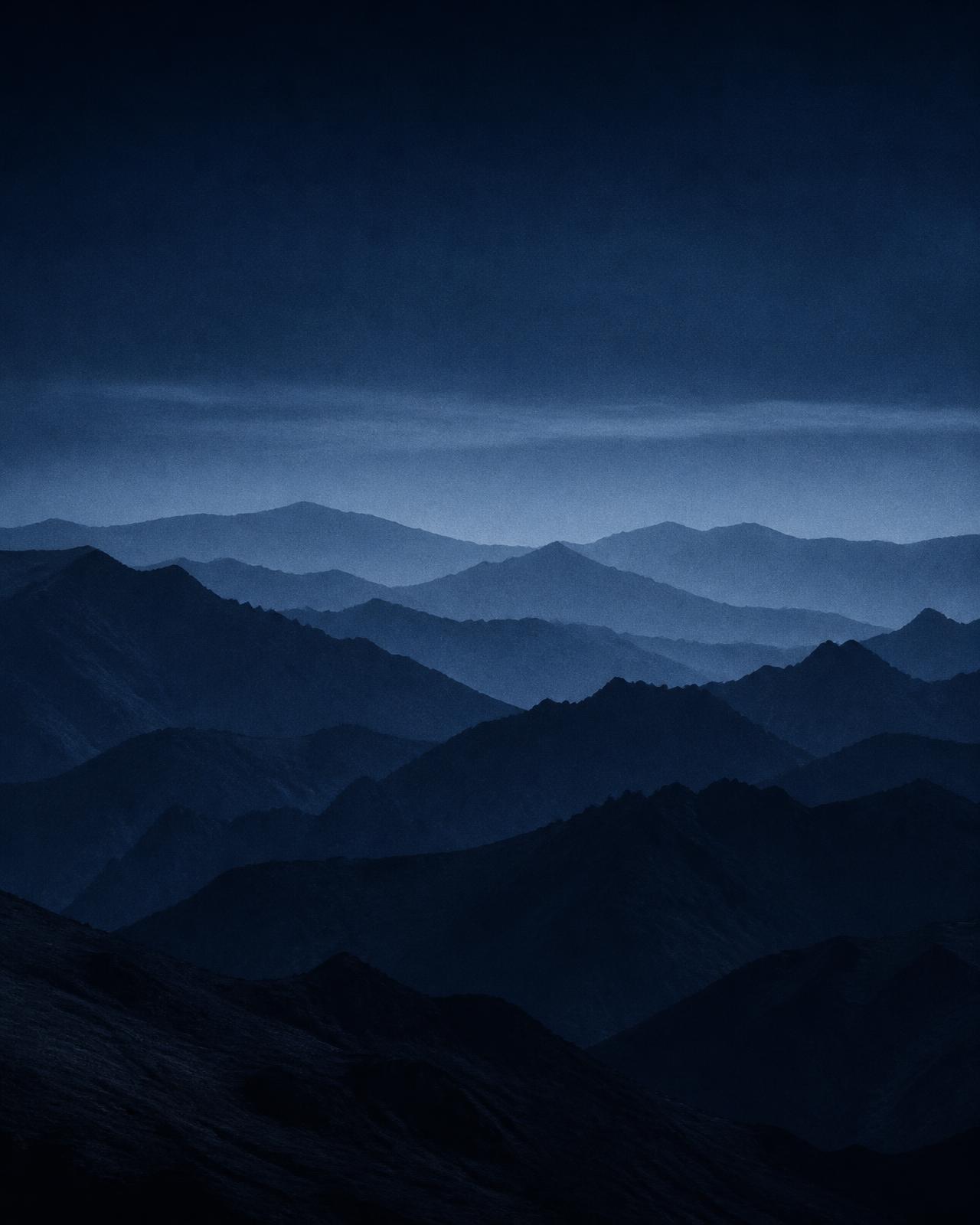 Layered distant mountain ridgelines fading into blue haze at dusk